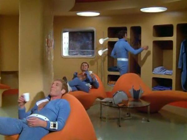 Moonbase - The scene when interceptor pilots slide down the tubes to reach their cockpits – is one of the most famous and beloved moments in retro sci-fi history. Battlestar Galactica (both the original 1978 version and the famous 2004 reboot) "borrowed" that exact concept!
The Low-Tech "Tube" Illusion - The sequence you are smiling about is a perfect example of how the British crew used pure physical tricks instead of expensive technology to make something look highly cool. Sometimes they succeeded, somethimes failed.
The Look - When the alien alarm rings, the three pilots jump out of their blue zipper-pyjama uniforms and slide feet-first down these bright metal chutes. The camera cuts, and suddenly they are sitting perfectly upright in their spaceship seats, ready to launch.
The Reality - There were no complex mechanics. The actors literally just sat on playground-style metal slides in the studio. They slid down into a mattress on the floor out of frame. Then, the camera would cut to a completely different set where they were already strapped into the cockpits. It was cheap, simple, and looked incredibly futuristic for 1970.
It Shaped Modern Sci-Fi
When Battlestar Galactica came out later, the American creators copied this exact pacing. They took that thrilling, fast-paced sequence of pilots scrambling from their quarters, jumping into launch tubes, and shooting out into space in their Viper fighters. By combining the glamorous, stylish lifestyle of the base with the gritty, mechanical reality of the pilots, UFO created the blueprint for how modern sci-fi handles military organizations in space.
It proved that you can have a show that is deeply focused on high-tech military strategy, while still ensuring the background is filled with enough visual style and glamour to keep the audience under that "hypnotic screen" spell.
The Contrast - Moonbase Beauties vs. The Boys' Club
The way the show balanced sex appeal with this "advanced space team" is where the corporate logic gets really funny. On one side of the Moonbase, you have the female officers wearing heavy makeup, purple hair, and tight silver miniskirts. They are the ones tracking the alien radar and typing on the computers. But the moment a real fight starts, the show shifts to the three male pilots in their blue pajamas and matching silver motorcycle helmets.
It was a total reflection of 1970 society. The creators wanted the high-fashion, liberal visual hook of the "Moonbase Beauties" to get people to watch the screen, but when it came to the actual space battles, they reverted back to a traditional, serious military setup. The pilots didn't look sexy or futuristic – they looked like a highly trained bobsled team or racecar drivers.