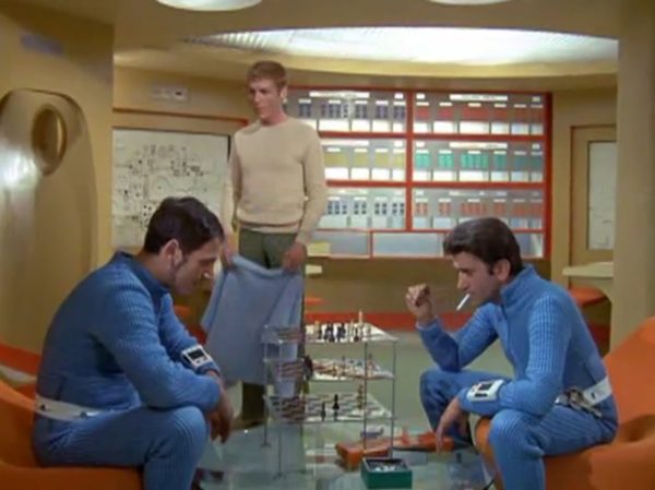 Moonbase - The scene when interceptor pilots slide down the tubes to reach their cockpits – is one of the most famous and beloved moments in retro sci-fi history. Battlestar Galactica (both the original 1978 version and the famous 2004 reboot) "borrowed" that exact concept!
The Low-Tech "Tube" Illusion - The sequence you are smiling about is a perfect example of how the British crew used pure physical tricks instead of expensive technology to make something look highly cool. Sometimes they succeeded, somethimes failed.
The Look - When the alien alarm rings, the three pilots jump out of their blue zipper-pyjama uniforms and slide feet-first down these bright metal chutes. The camera cuts, and suddenly they are sitting perfectly upright in their spaceship seats, ready to launch.
The Reality - There were no complex mechanics. The actors literally just sat on playground-style metal slides in the studio. They slid down into a mattress on the floor out of frame. Then, the camera would cut to a completely different set where they were already strapped into the cockpits. It was cheap, simple, and looked incredibly futuristic for 1970.
It Shaped Modern Sci-Fi
When Battlestar Galactica came out later, the American creators copied this exact pacing. They took that thrilling, fast-paced sequence of pilots scrambling from their quarters, jumping into launch tubes, and shooting out into space in their Viper fighters. By combining the glamorous, stylish lifestyle of the base with the gritty, mechanical reality of the pilots, UFO created the blueprint for how modern sci-fi handles military organizations in space.
It proved that you can have a show that is deeply focused on high-tech military strategy, while still ensuring the background is filled with enough visual style and glamour to keep the audience under that "hypnotic screen" spell.
The Contrast - Moonbase Beauties vs. The Boys' Club
The way the show balanced sex appeal with this "advanced space team" is where the corporate logic gets really funny. On one side of the Moonbase, you have the female officers wearing heavy makeup, purple hair, and tight silver miniskirts. They are the ones tracking the alien radar and typing on the computers. But the moment a real fight starts, the show shifts to the three male pilots in their blue pajamas and matching silver motorcycle helmets.
It was a total reflection of 1970 society. The creators wanted the high-fashion, liberal visual hook of the "Moonbase Beauties" to get people to watch the screen, but when it came to the actual space battles, they reverted back to a traditional, serious military setup. The pilots didn't look sexy or futuristic – they looked like a highly trained bobsled team or racecar drivers.
