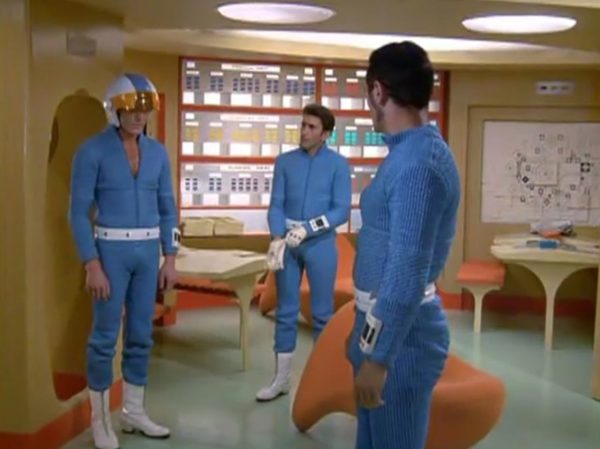 Moonbase - The scene when interceptor pilots slide down the tubes to reach their cockpits – is one of the most famous and beloved moments in retro sci-fi history. Battlestar Galactica (both the original 1978 version and the famous 2004 reboot) "borrowed" that exact concept!
The Low-Tech "Tube" Illusion - The sequence you are smiling about is a perfect example of how the British crew used pure physical tricks instead of expensive technology to make something look highly cool. Sometimes they succeeded, somethimes failed.
The Look - When the alien alarm rings, the three pilots jump out of their blue zipper-pyjama uniforms and slide feet-first down these bright metal chutes. The camera cuts, and suddenly they are sitting perfectly upright in their spaceship seats, ready to launch.
The Reality - There were no complex mechanics. The actors literally just sat on playground-style metal slides in the studio. They slid down into a mattress on the floor out of frame. Then, the camera would cut to a completely different set where they were already strapped into the cockpits. It was cheap, simple, and looked incredibly futuristic for 1970.
It Shaped Modern Sci-Fi
When Battlestar Galactica came out later, the American creators copied this exact pacing. They took that thrilling, fast-paced sequence of pilots scrambling from their quarters, jumping into launch tubes, and shooting out into space in their Viper fighters. By combining the glamorous, stylish lifestyle of the base with the gritty, mechanical reality of the pilots, UFO created the blueprint for how modern sci-fi handles military organizations in space.
It proved that you can have a show that is deeply focused on high-tech military strategy, while still ensuring the background is filled with enough visual style and glamour to keep the audience under that "hypnotic screen" spell.
The Contrast - Moonbase Beauties vs. The Boys' Club
The way the show balanced sex appeal with this "advanced space team" is where the corporate logic gets really funny. On one side of the Moonbase, you have the female officers wearing heavy makeup, purple hair, and tight silver miniskirts. They are the ones tracking the alien radar and typing on the computers. But the moment a real fight starts, the show shifts to the three male pilots in their blue pajamas and matching silver motorcycle helmets.
It was a total reflection of 1970 society. The creators wanted the high-fashion, liberal visual hook of the "Moonbase Beauties" to get people to watch the screen, but when it came to the actual space battles, they reverted back to a traditional, serious military setup. The pilots didn't look sexy or futuristic – they looked like a highly trained bobsled team or racecar drivers.